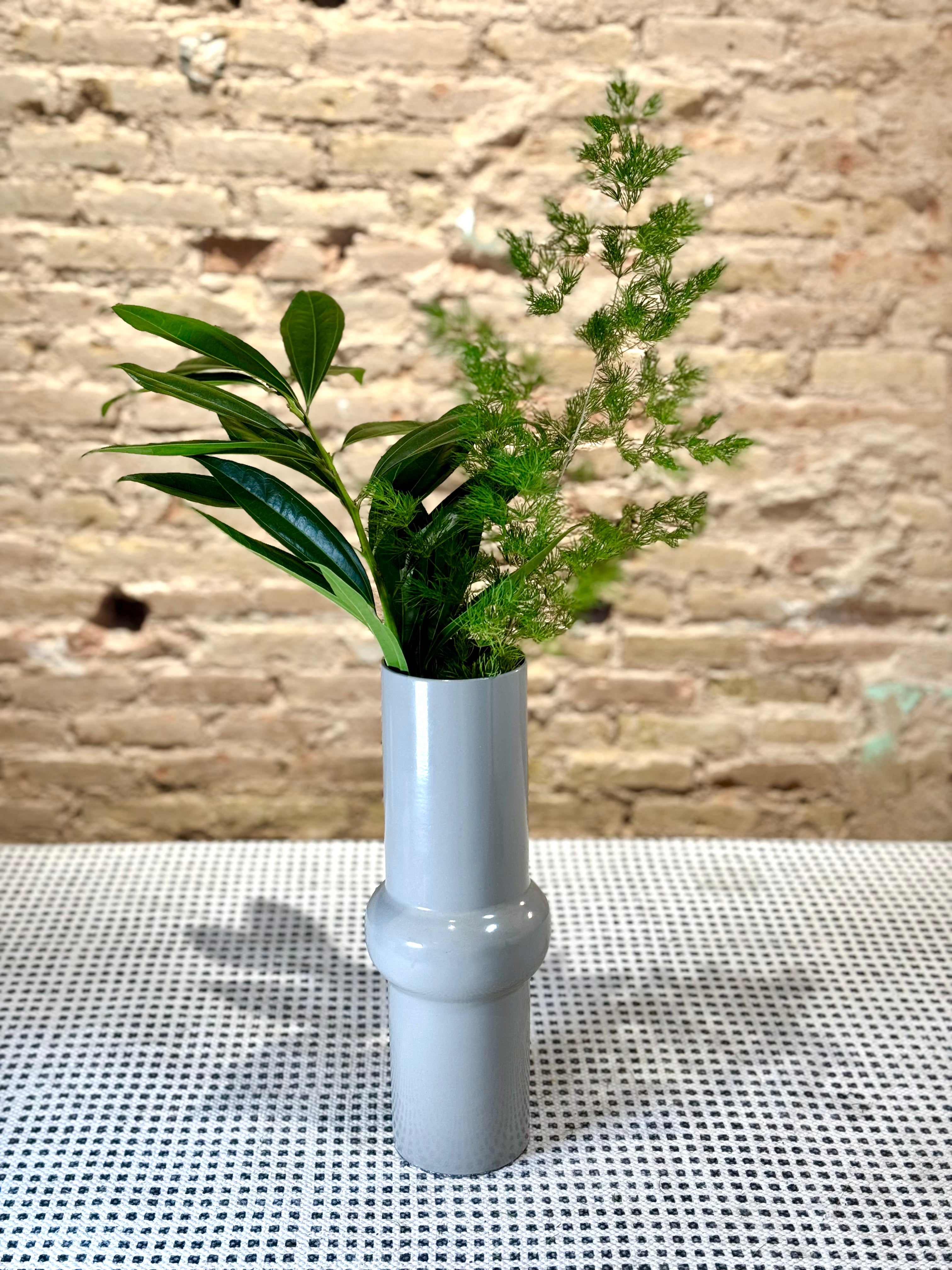 Florero metálico gris en forma tubular