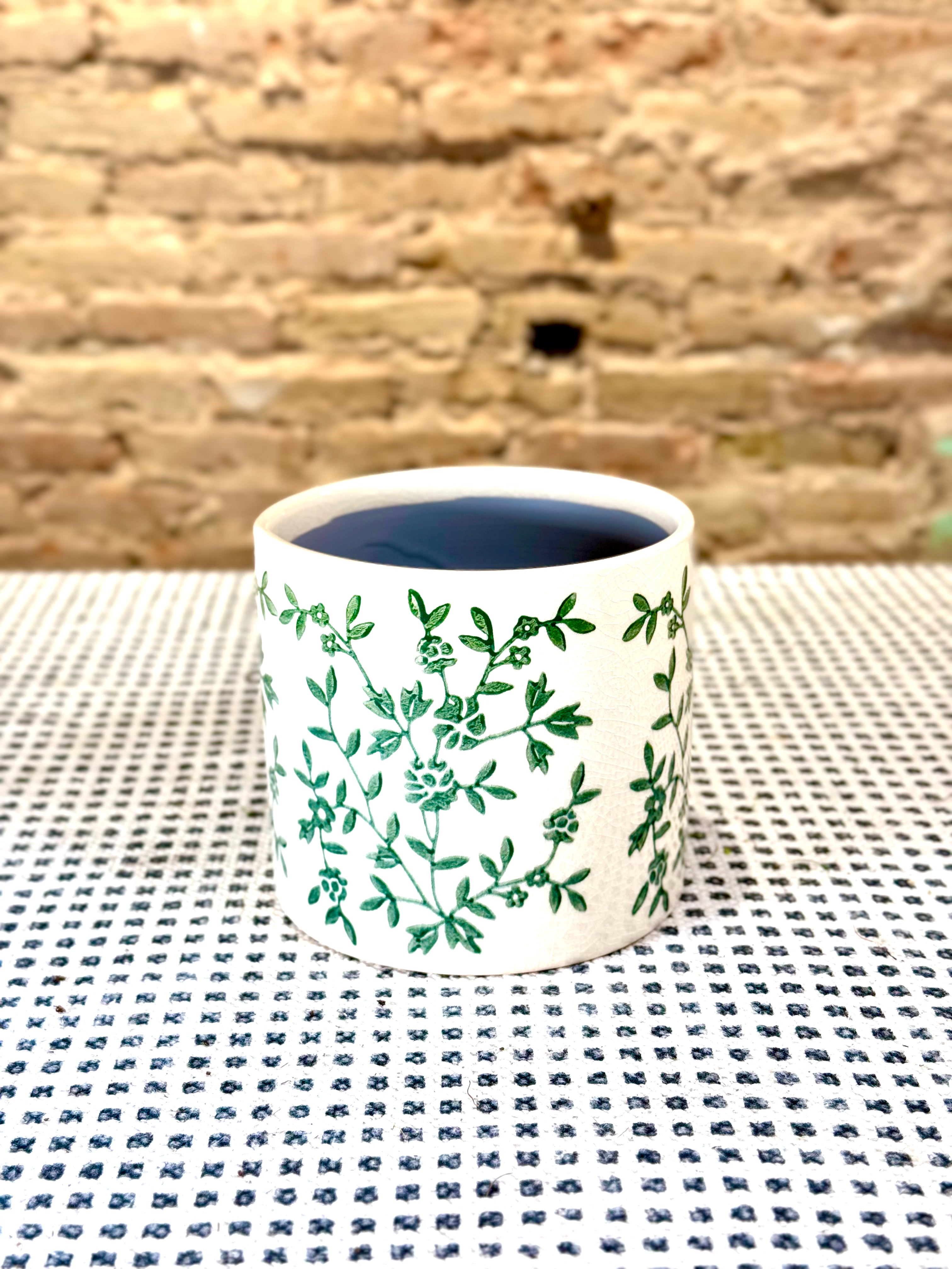 Portamacetas blanco con ramas verdes